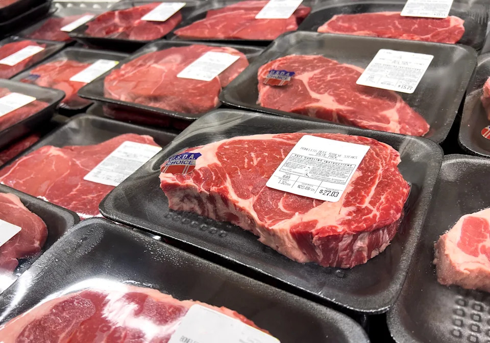 Packages of raw steak are placed in the grocery store, displaying quality and price labels.