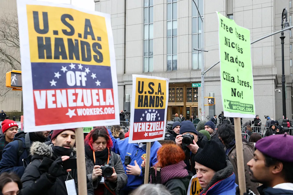 Protesters hold signs that read, "USA Leaves Venezuela" and "Free Ites, Nickis Madro Cilia Flres, No!" in a street show