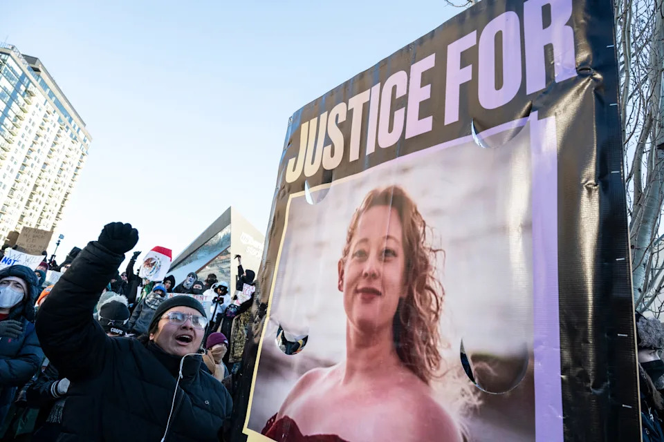 Protesters holding a "Justice for" sign with a photo of a woman on it, showing a city street