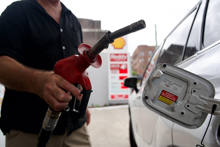 A man is holding a can of petrol next to his car.