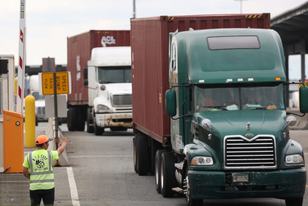 A worker directs traffic after trucks are loaded in Newark