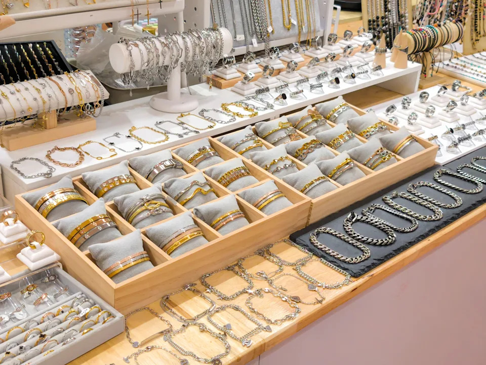 A display of various bracelets and bangles on the jewelry counter, arranged with wooden trays and chairs.